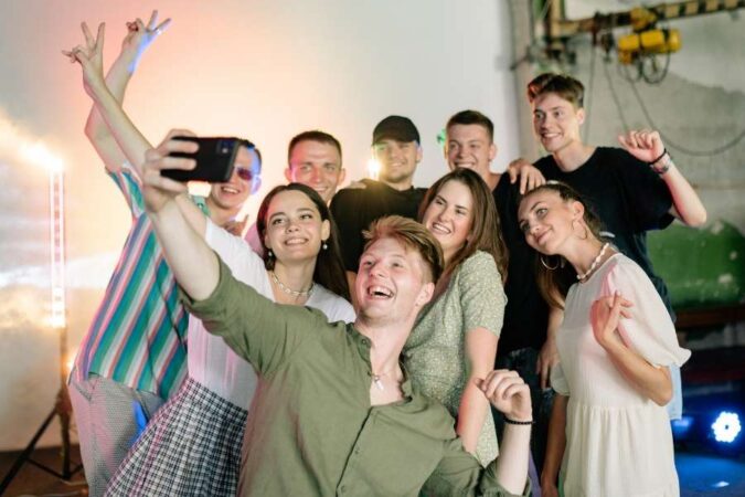 Un groupe d'amis souriants se prend en photo en mode selfie lors d'une soirée animée.